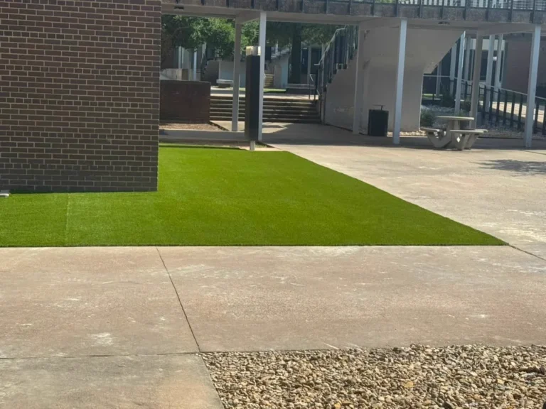 Commercial synthetic grass installed along a campus walkway and seating area in Denison, Texas