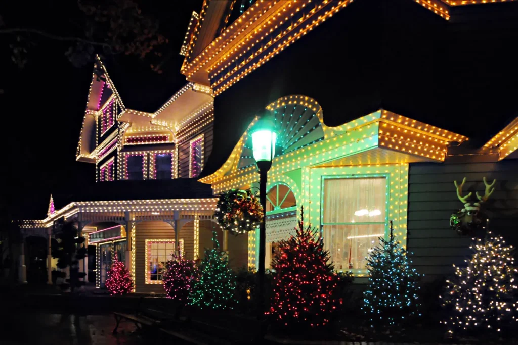 Full-color Christmas light display — multicolor rooflines, outlined windows, and lit yard trees
