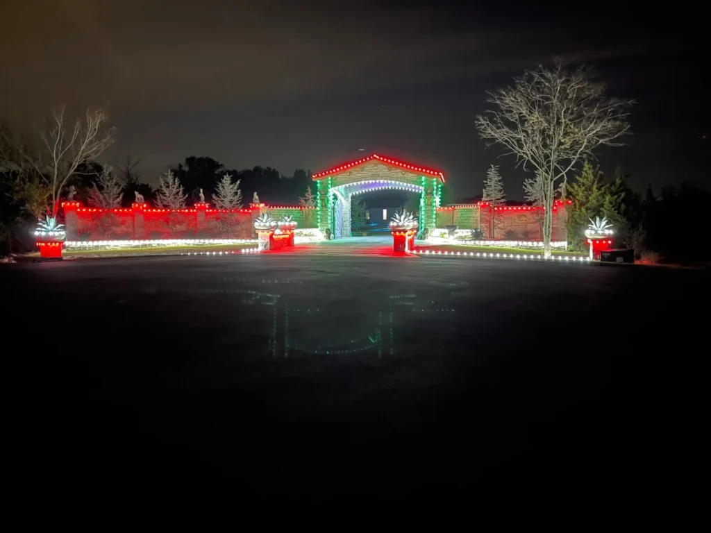 Red, white, and green C9 Christmas lights on a stone entrance gate and estate wall in North Texas